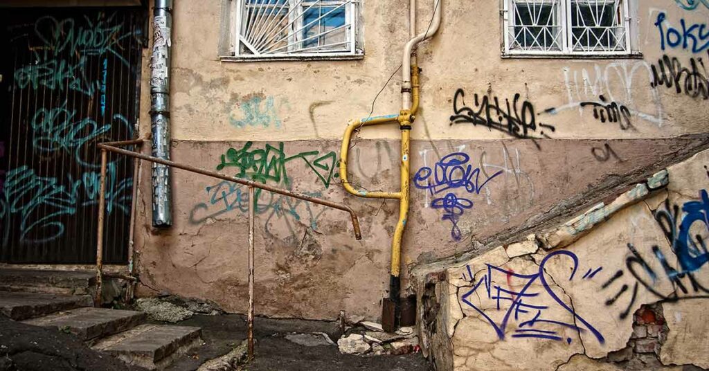 Eine alte Hauswand mit Graffiti und rostigem Treppengeländer und Gitter - Sanierungsstau