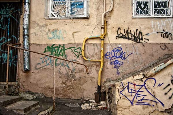 Eine alte Hauswand mit Graffiti und rostigem Treppengeländer und Gitter - Sanierungsstau