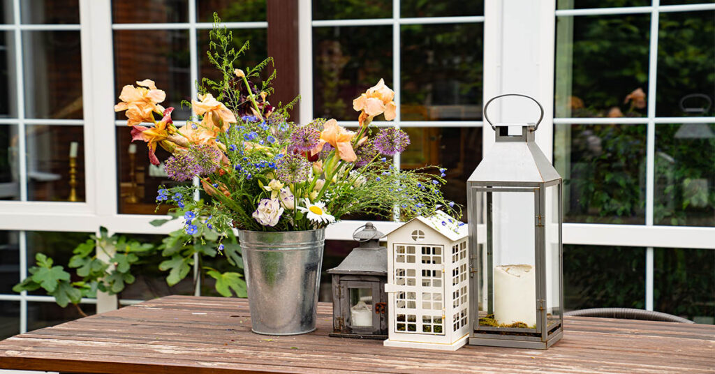 Ein Holztisch mit Blumenstrauß und Kerzenhaltern - Jetzt Immobilie kaufen