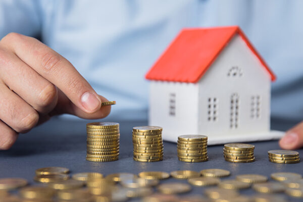 man hand coins with house model on desk; Immobilienkauf