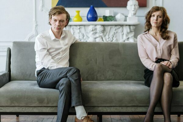 Ein Paar hat die Scheidung beschlossen und sitzt unglücklich auf dem Sofa in seinem Wohnzimmer | Scheidungsimmobilie